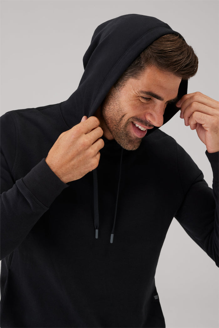 Close up view of a man wearing Ace Pullover Hooded Sweatshirt with the hood on his head