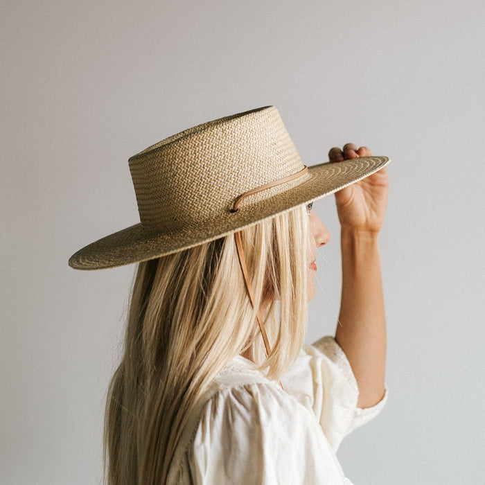 Woman wearing a cream straw hat with a band and a white top, facing sideways against a plain background #color_cream