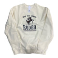 A bone-colored sweatshirt with the text 'NOT MY FIRST RODEO JACKSON HOLE WYOMING' printed on the front.