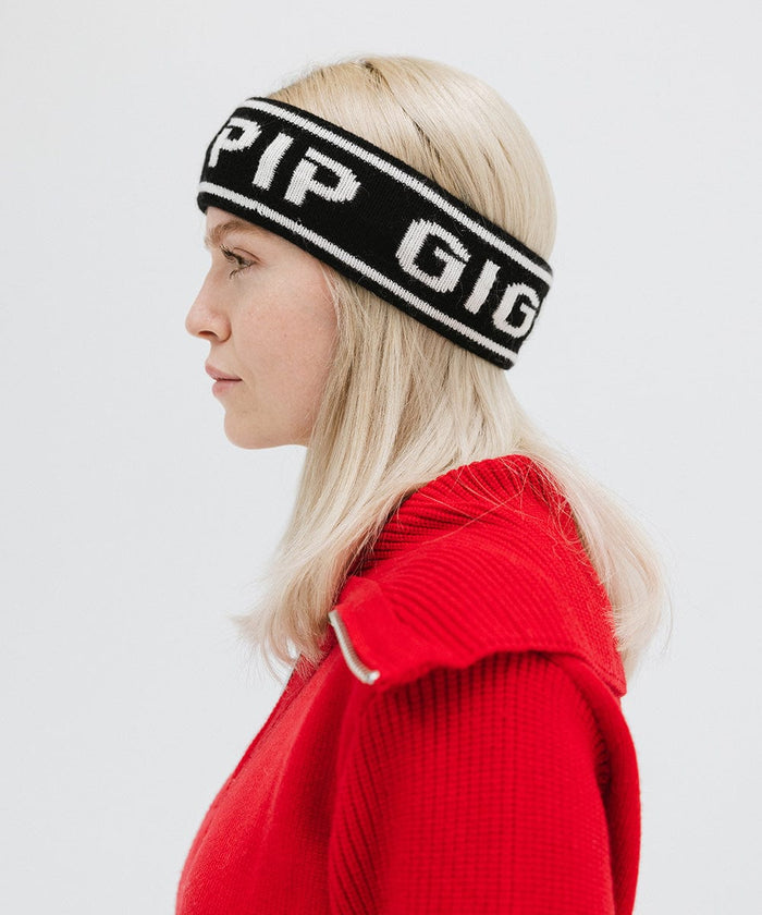 Woman wearing a black headband with 'GIGI PIP' text and a red jacket, facing sideways against a plain background #color_black