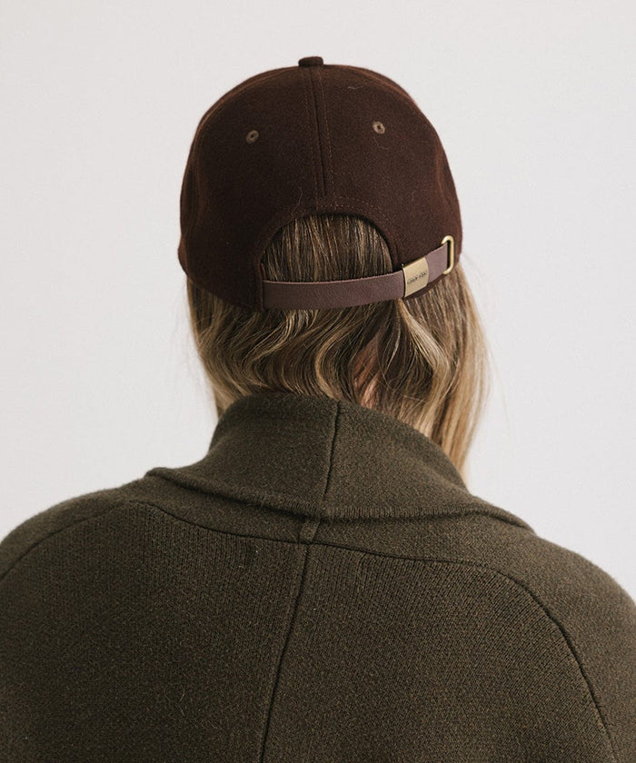 Person wearing a brown cap and a brown coat against a plain background  #color_brown