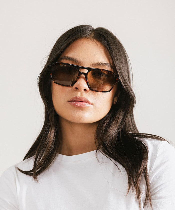 Woman wearing sunglasses with a plain background #color_tortoise