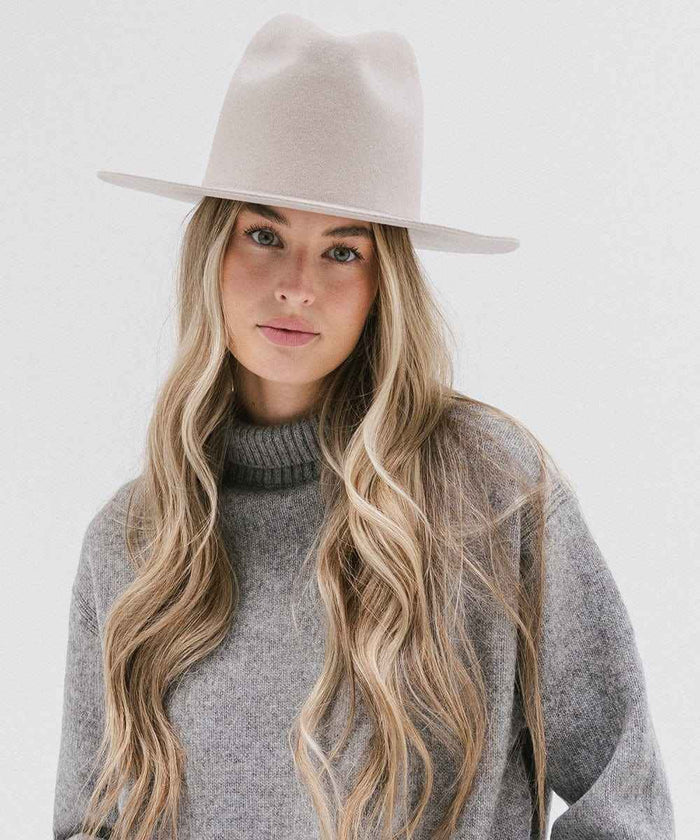 Woman wearing an ivory colored hat and grey sweater against a white background #color_ivory