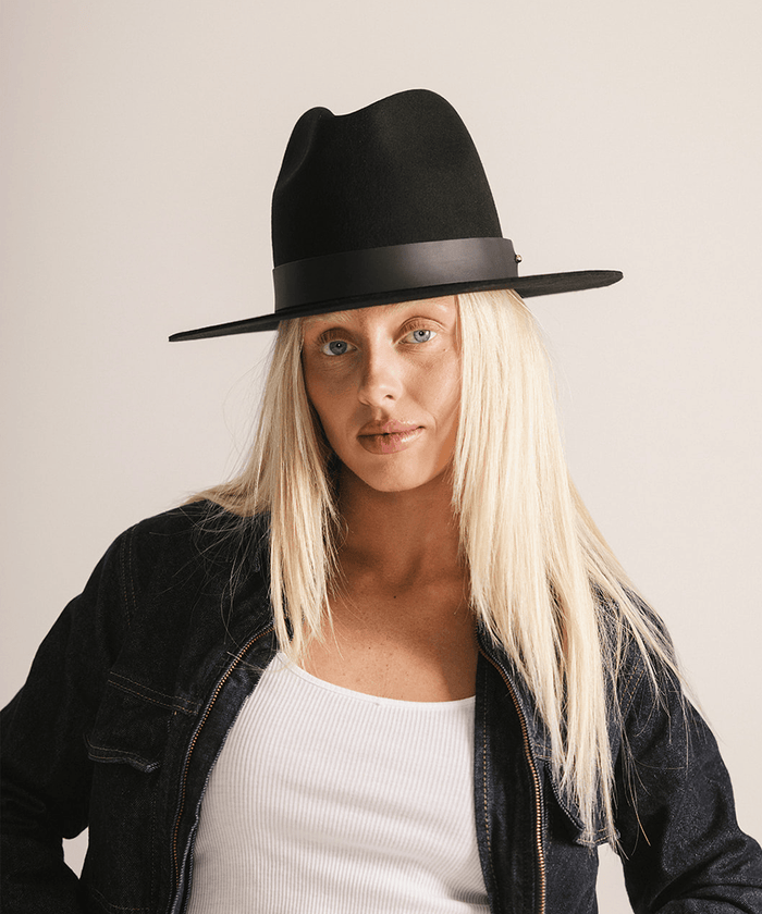 Woman wearing a black tall fedora hat against a plain background #color_black