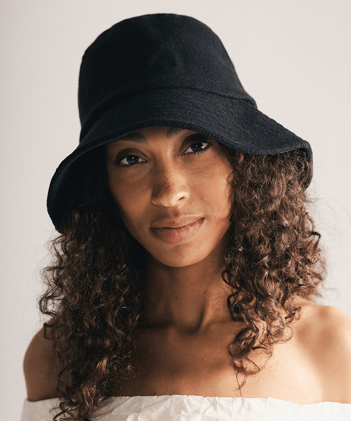 Woman wearing a black bucket hat against a plain background #color_black