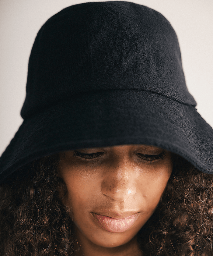 Woman wearing a black bucket hat against a plain background #color_black