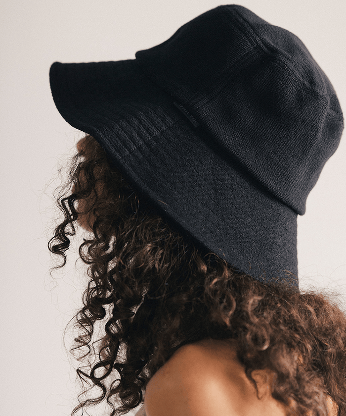 Woman wearing a black bucket hat against a plain background #color_black