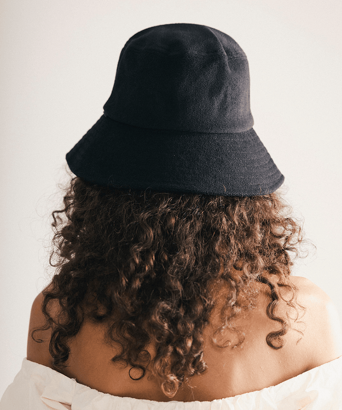Woman wearing a black bucket hat against a plain background #color_black