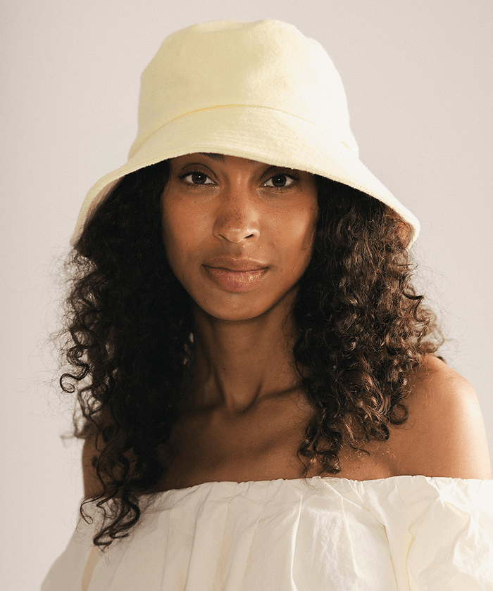 Woman wearing a yellow bucket hat against a plain background #color_ butter yellow