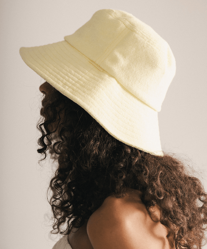 Woman wearing a yellow bucket hat against a plain background #color_ butter yellow