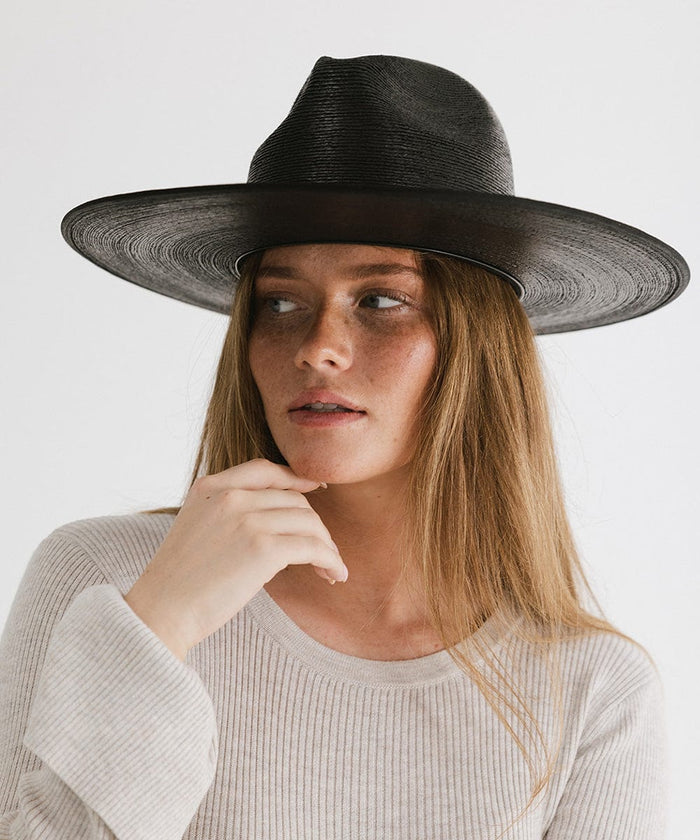 Woman wearing a black wide brim fedora hat and a grey t-shirt, posing against a plain background #color_limited edition black
