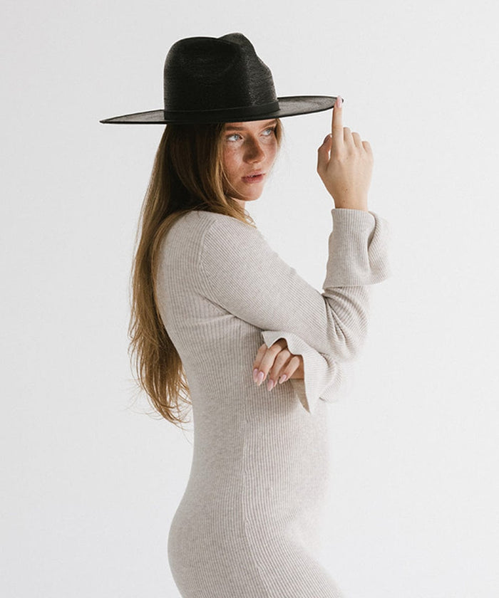 Woman with long hair wearing a black wide brim fedora hat with a hat band and a grey top, looking sideways against a plain background #color_limited edition black