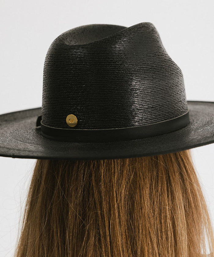 Person wearing a black wide brim fedora hat with a hat band against a plain background #color_limited edition black