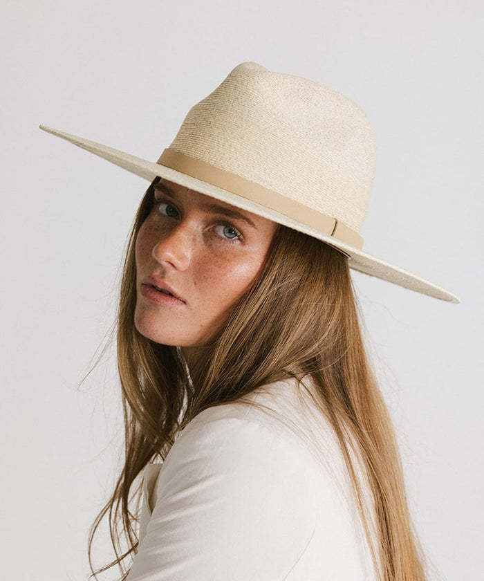 Woman wearing a natural colored wide brim fedora hat with a hat band against a plain background #color_natural