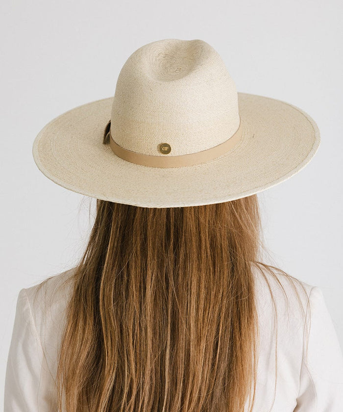 Person with long hair wearing a natural colored wide brim fedora hat with a hat band, facing behind against a plain background #color_natural