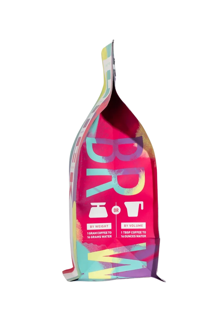 Side view of a vibrant multicolor coffee bag with abstract artwork and a folded top.