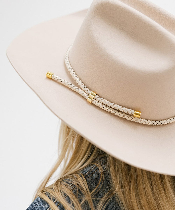 Close up image of a person wearing a cream hat with an ivory colored braided hat band against a plain background #color_ivory
