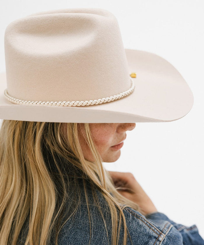 Woman wearing a cream hat with an ivory colored braided hat band and a denim shirt, facing sideways against a plain background #color_ivory