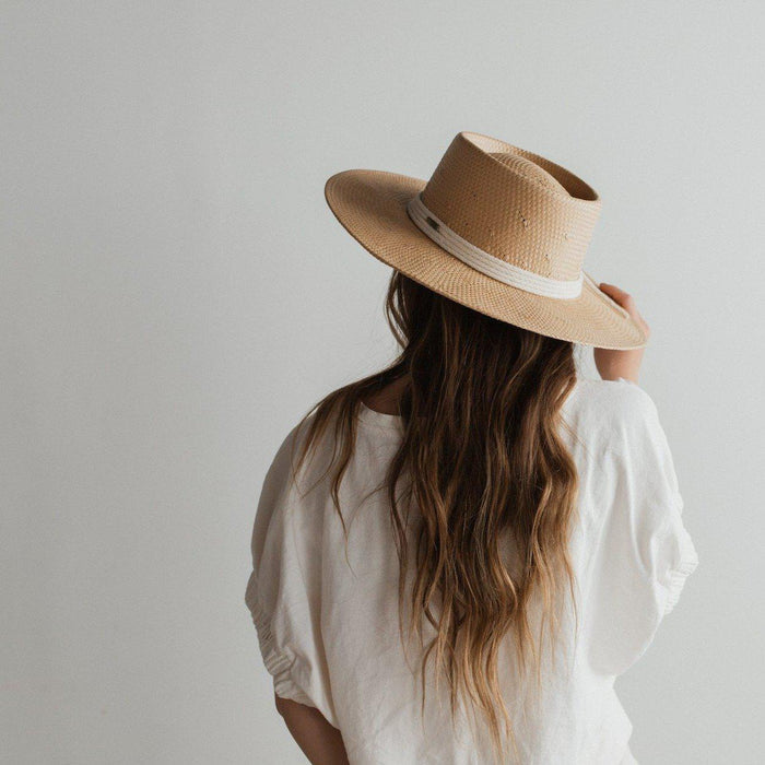 Woman wearing a natural colored straw hat with a white rope hat band and a white top, facing behind against a plain background #color_natural