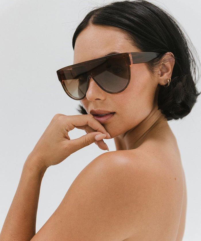 Woman wearing amber colored sunglasses posing against a plain background #color_amber