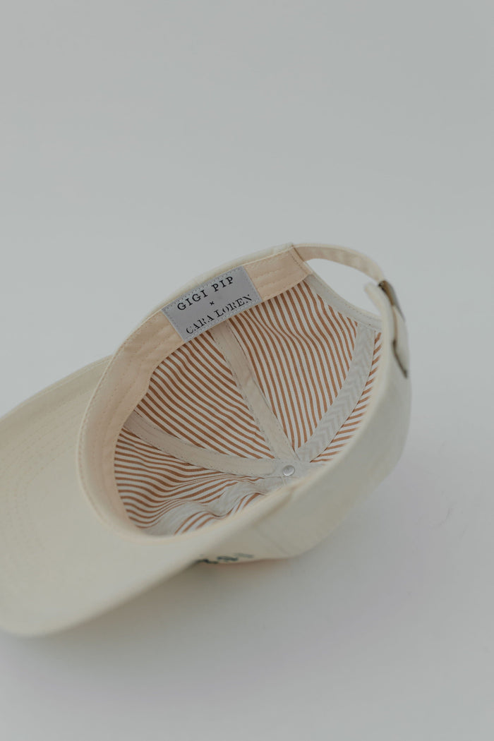 A cream ball cap with the brand label, upside down on a plain background #color_cream