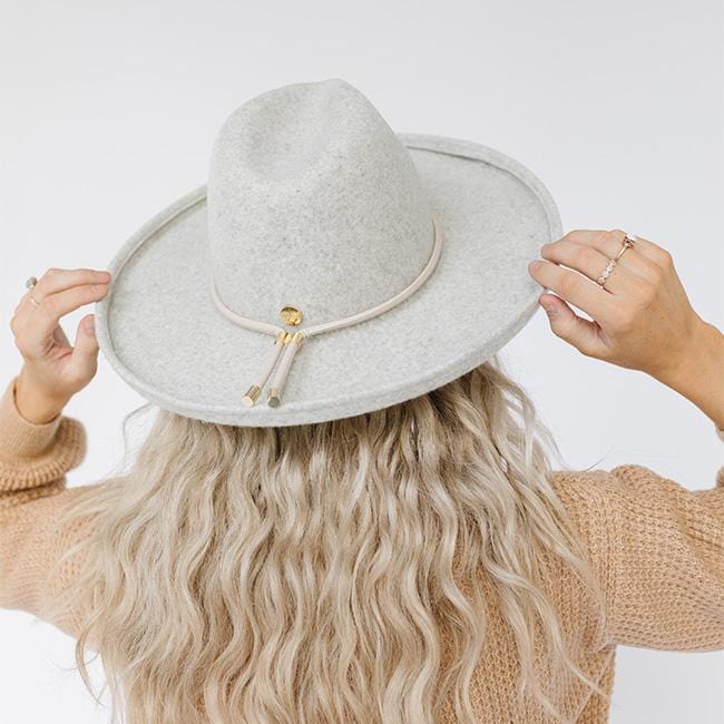 Woman wearing a heather grey pencil brim fedora hat with a hat band  and a light brown sweatshirt against a plain background  #color_heather grey