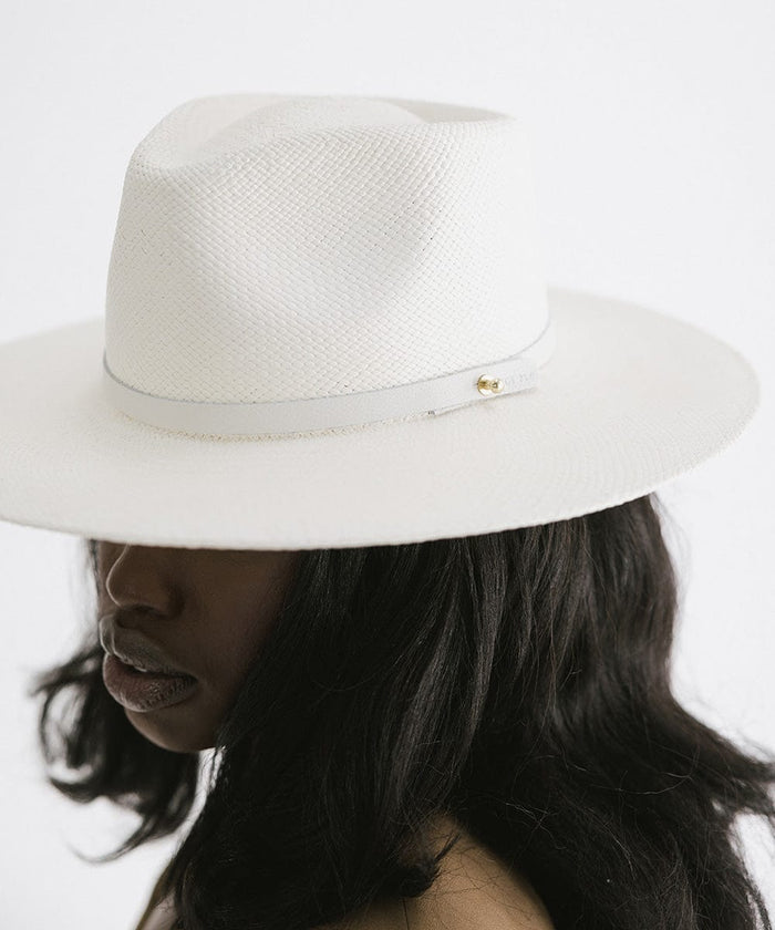 Woman wearing a white straw hat with a hat band against a plain background #color_white