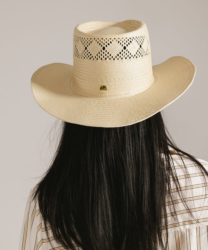 Beige straw hat worn by a person with long dark hair on a plain background #color_natural