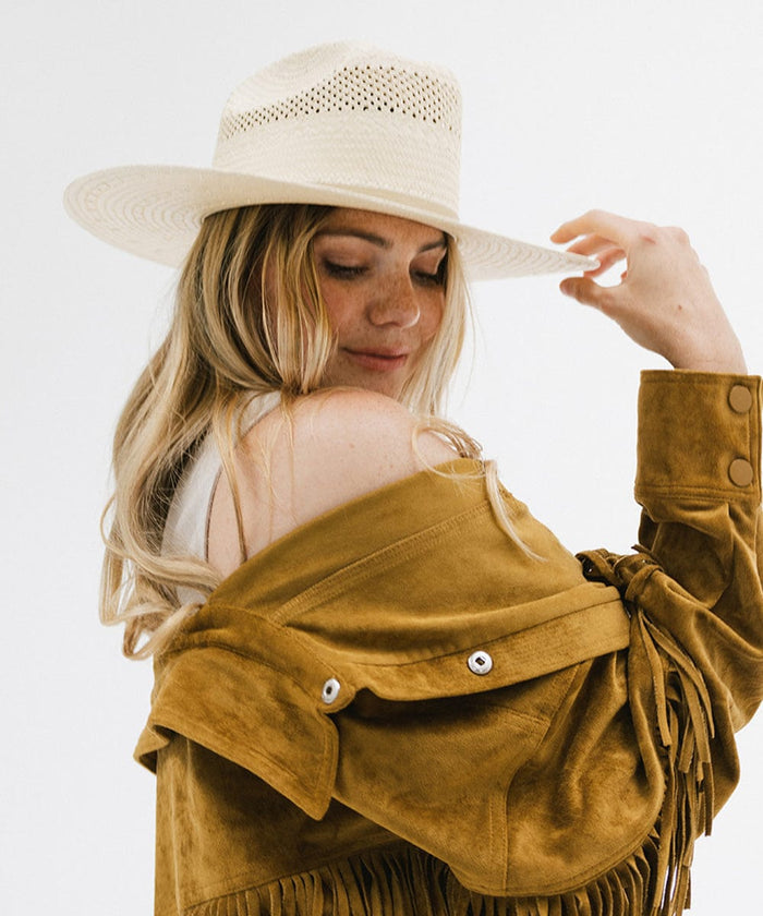 Woman wearing a natural colored straw cowboy hat and a mustard colored jacket, posing against a plain background  #color_natural