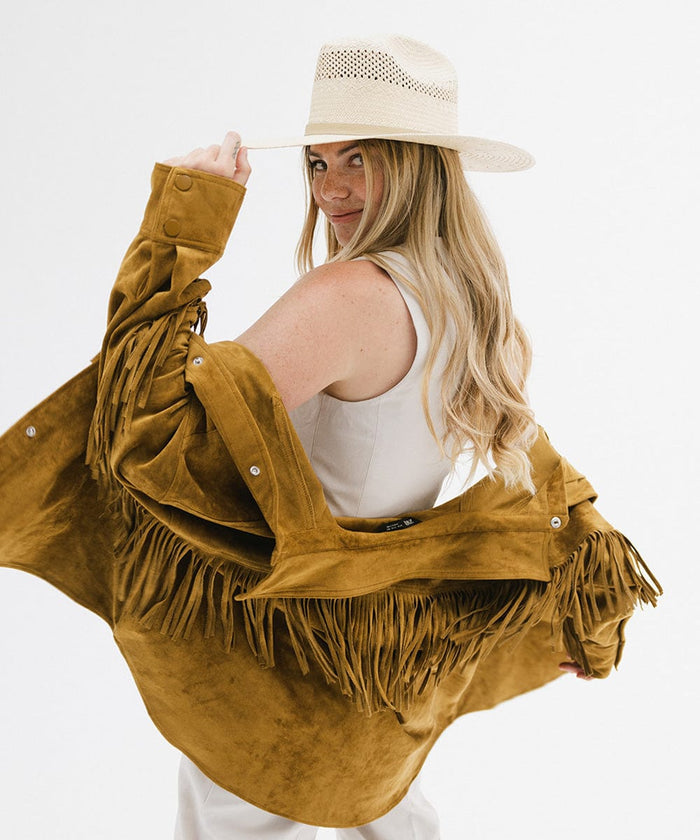 Woman wearing a natural colored straw cowboy hat, a white top with a mustard jacket, posing against a plain background  #color_natural