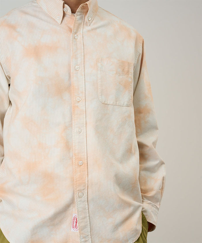 Model wearing a Gramicci peach Bleach Stripe colored Classic Oxford Bleached Shirt against a light-tone background.