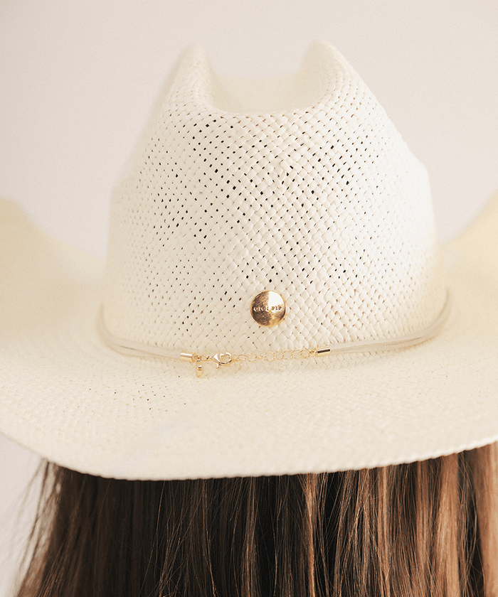 Woman wearing a beige straw hat with a decorative band in a white background #color_cream