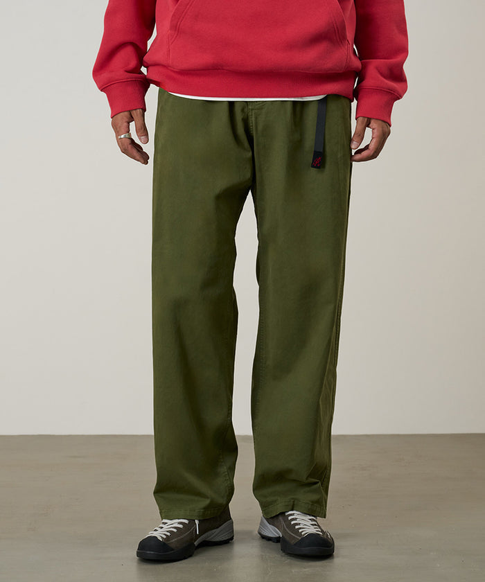 Model wearing olive Gramicci Cliff Pants and a red hoodie on a light-tone background.