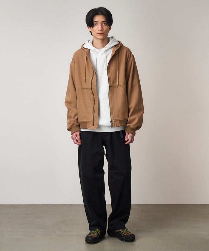 Model wearing black Gramicci Cliff Pants and a brown jacket on a light-tone background.