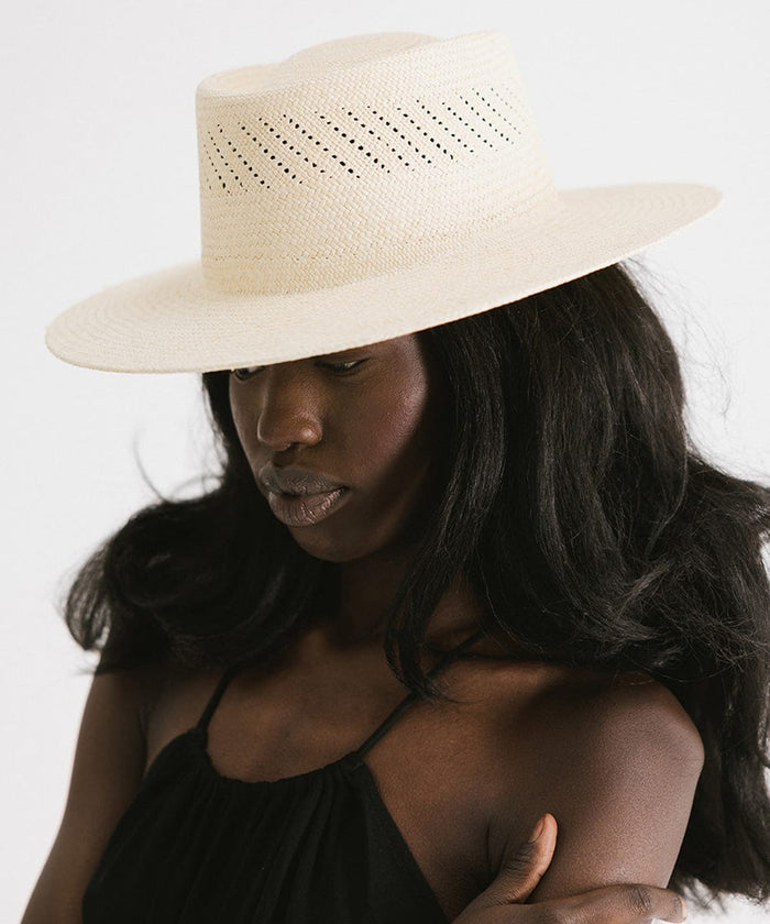 Woman wearing a natural colored straw hat and a black top against a plain background #color_natural