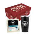A red gift box labeled The Front Bottoms coffee and chaos sits behind a black tumbler and a bag of The Front Bottoms Roast Coffee by Movement Roasters, both with The Front Bottoms’ logo.