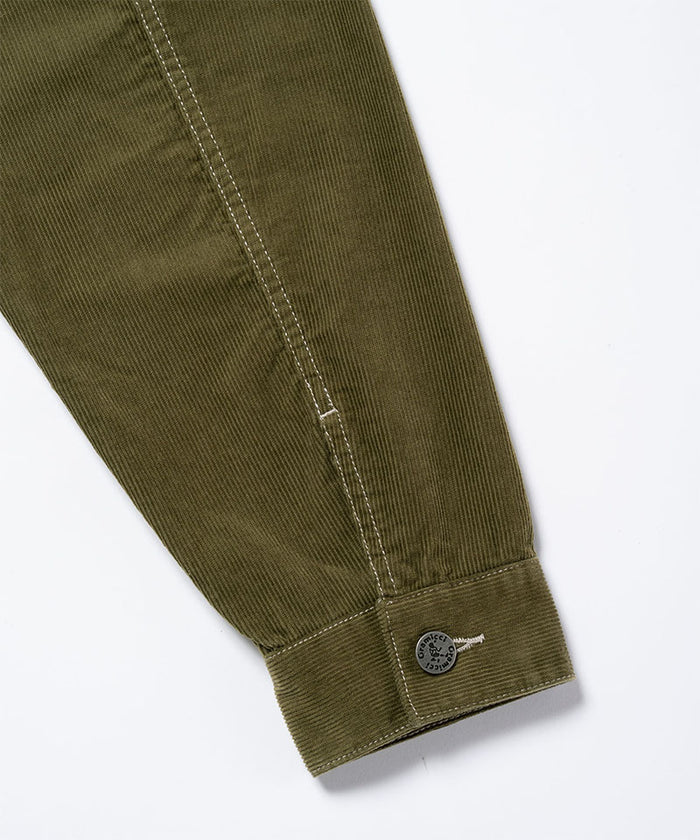 Close-up of the cuff and sleeve on a olive Gramicci Corduroy Trucker Jacket showing branded buttons on a light-tone background.