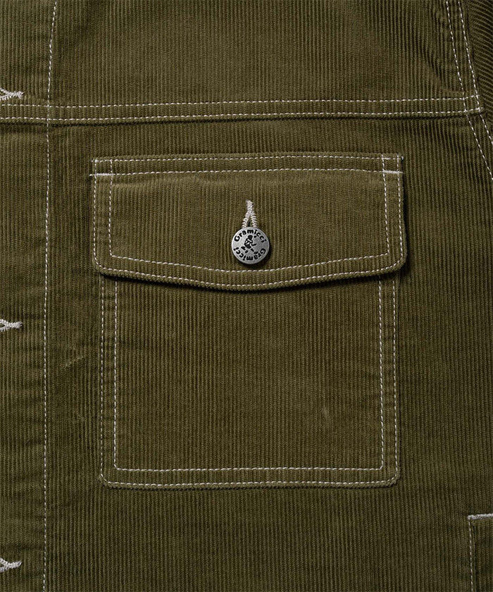 Close-up view of a Gramicci Corduroy Trucker Jacket pocket in olive on a light-tone background.