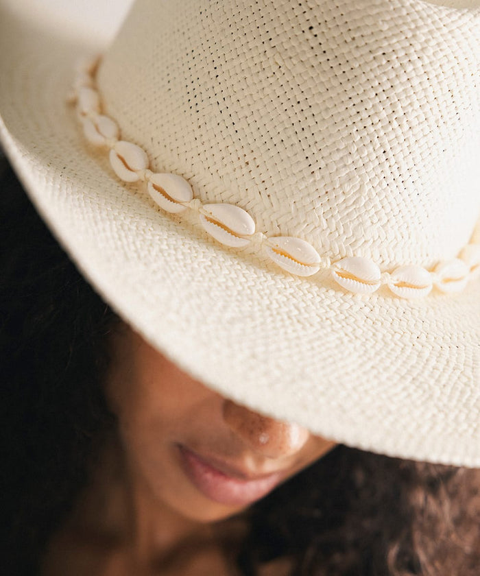 Close-up of a woman wearing a white hat with shell embellishments #color_natural