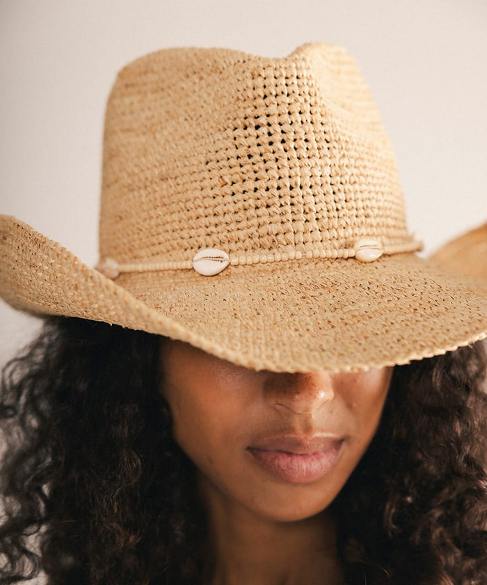Woman wearing a straw hat with a decorative band against a plain background #color_cream