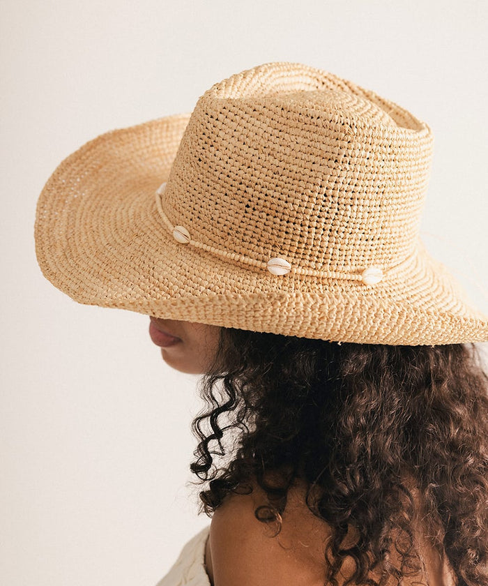 Woman wearing a straw hat with a decorative band against a plain background #color_cream