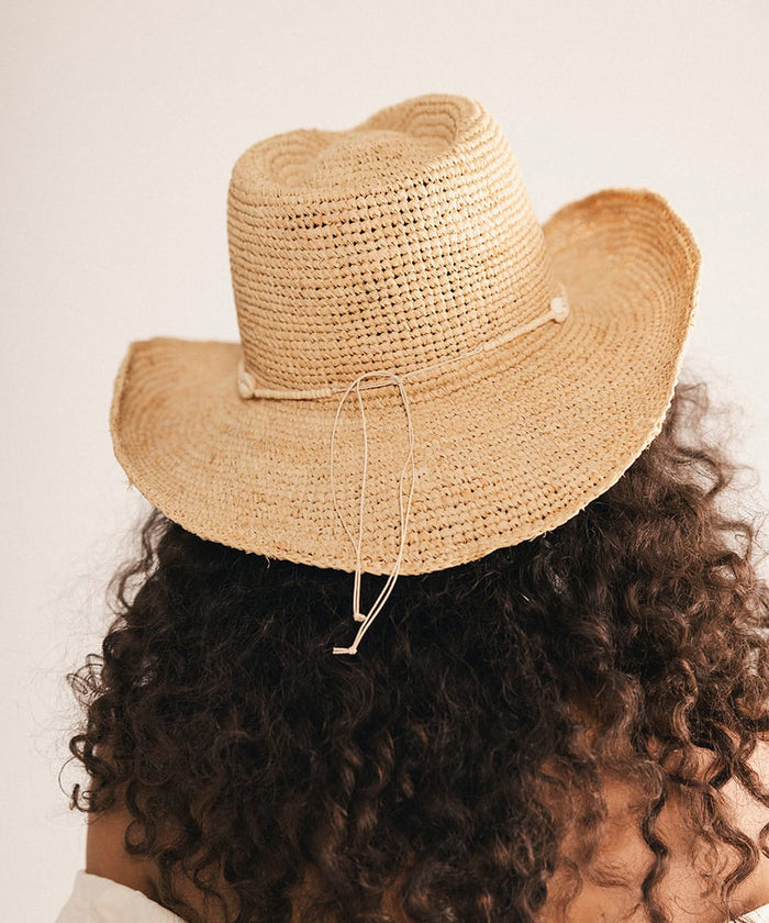 Woman wearing a straw hat with a decorative band against a plain background #color_cream