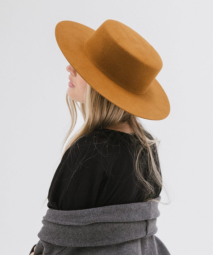 Woman wearing a brown boater-style hat and a black t-shirt, facing sideways against a plain background #color_brown