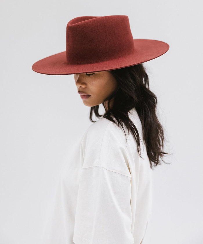 Woman wearing a rusty red wide brim felt hat with a triangle crown and a white t-shirt, posing against a white background #color_rusty red