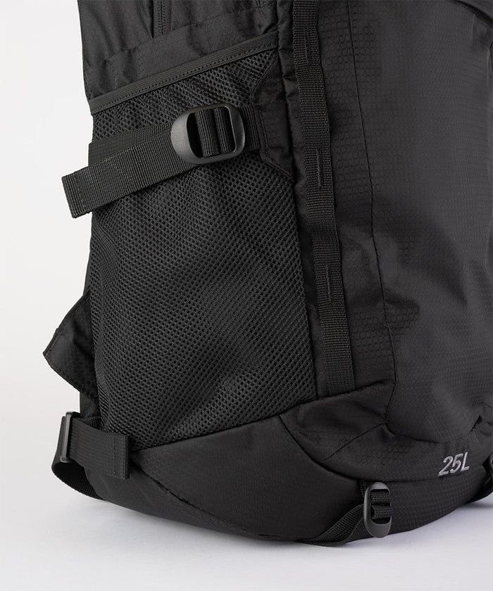 Close-up of Gramicci Day Pack 25L backpack in the color black against a light-tone background.