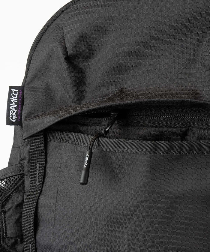Close-up of Gramicci Day Pack 25L backpack in the color black against a light-tone background.