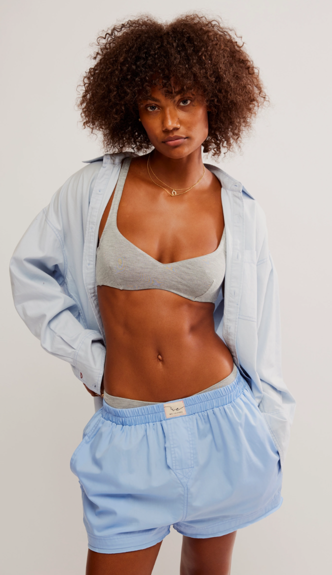 A person wearing a placid blue high-rise boxer shorts with an elastic waistband and a logo tag detail.