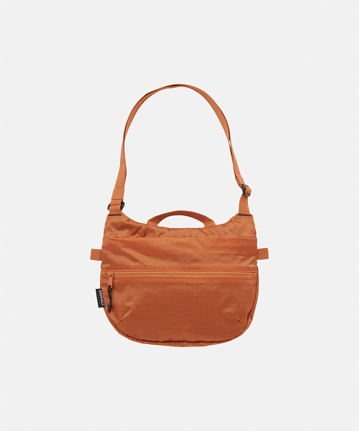 Orange Gramicci Field Sacoche bag 
against a light-tone background.
