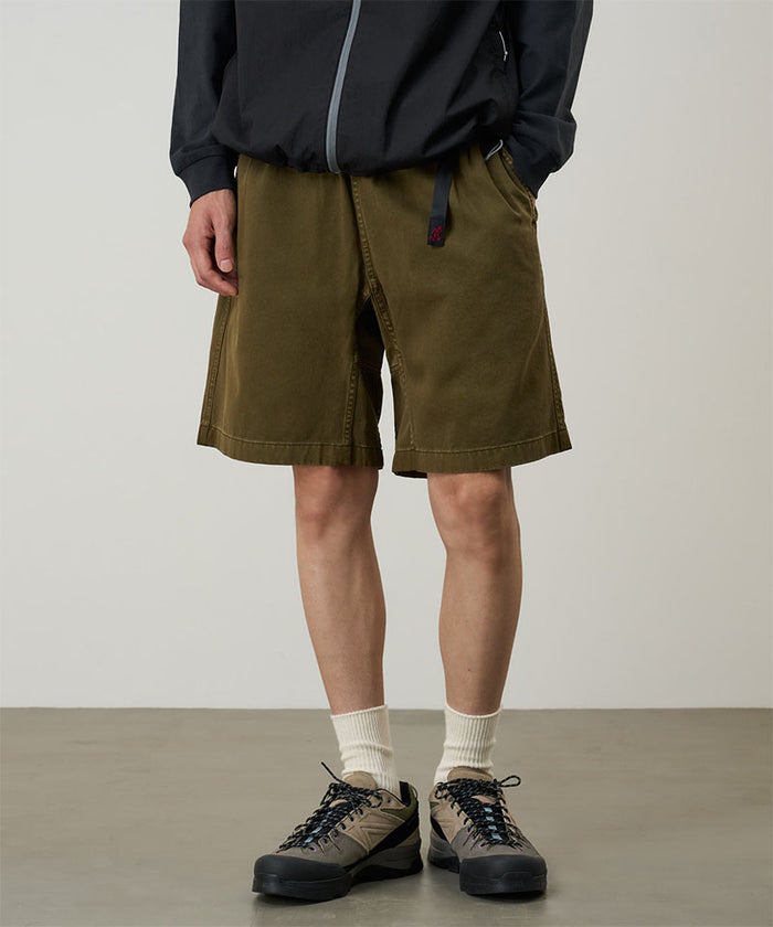 Model wearing bark pigment dye Gramicci G-Shorts and a black jacket on a light-tone background.