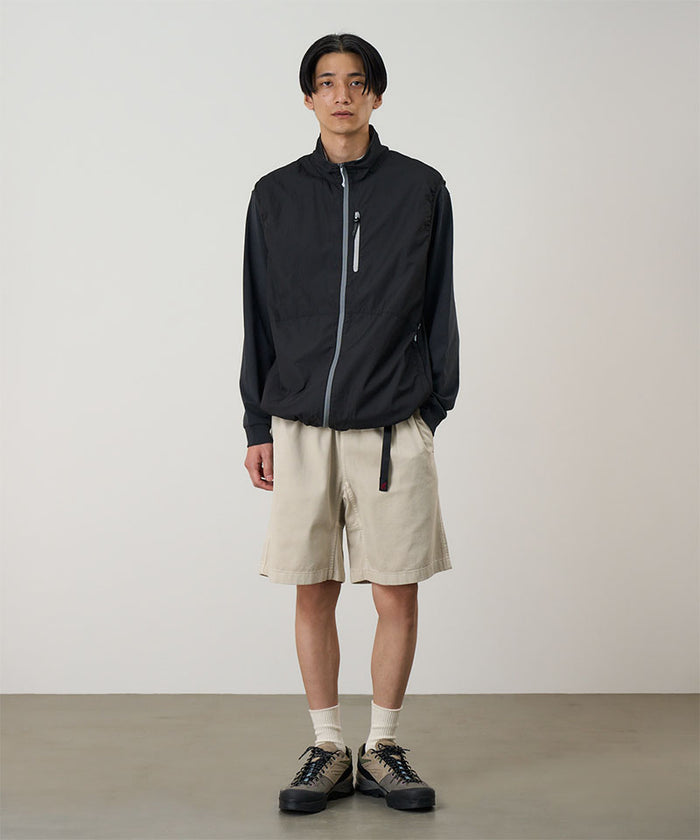 Model wearing sand pigment dye Gramicci G-Shorts and a black jacket on a light-tone background.